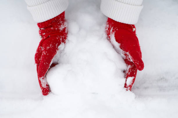 istock Girl's hands in red gloves making snowball 1184885143