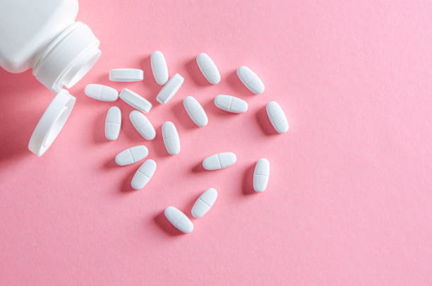 istock A white plastic container with white tablets lies on a multi-colored background next to white tablets 1184886515