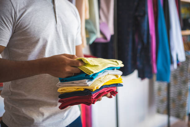 salesman holding shirts to show customer - adult variation boutique occupation imagens e fotografias de stock