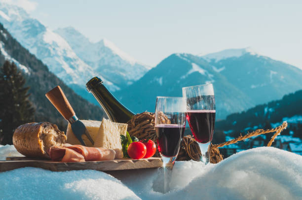 comida y bebida tradicional italiana al aire libre en el día soleado de invierno. romántico picnic alpino en dolomitas con fondo de montañas, baguette de queso lambrusco y jamón en la nieve. - tourism panoramas winter travel locations fotografías e imágenes de stock