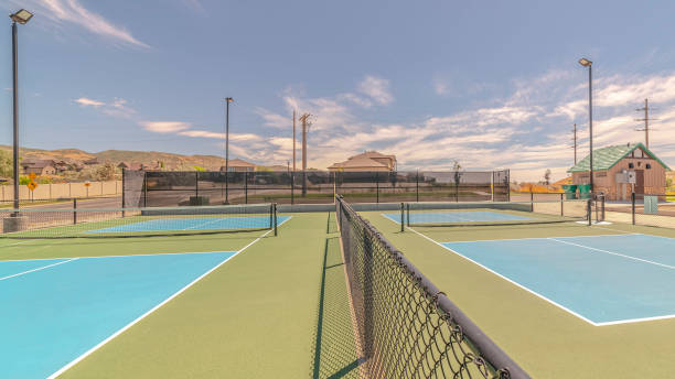 istock Panorama frame Empty tennis courts on sunny day divided by fence 1184896090