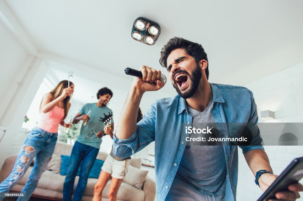 Karaoke Party Group of friends playing karaoke at home.Group of friends having party together at home. Singing Stock Photo