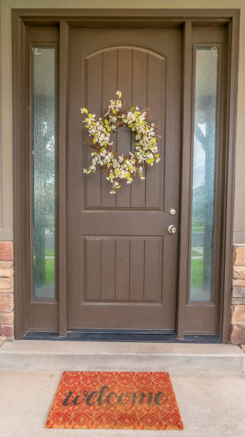 istock Vertical frame Flower wreath on a brown front door with sidelights and windows on both sides 1184897594