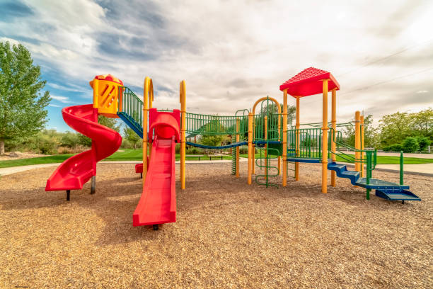 istock Focus on empty childrens playground at a park with red slides and climbing bars 1184898691