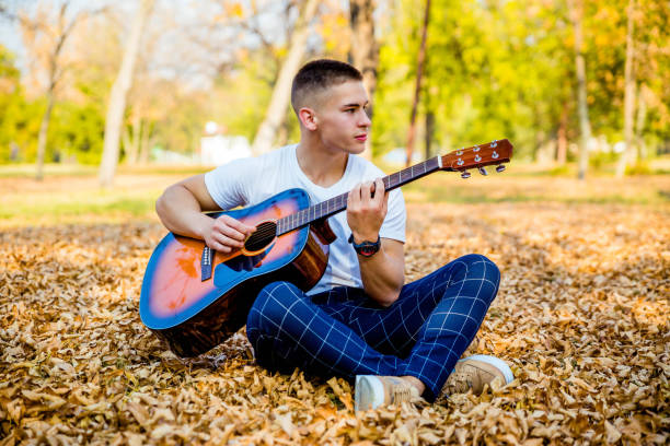 istock Young man playing acoustic guitar in park 1184908591