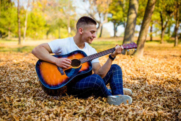 istock Young man playing acoustic guitar in park 1184908599