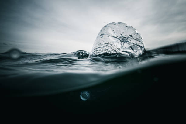Plastic in the ocean Underwater shot of plastic bottle floating around in the ocean. With copy space microplastic photos stock pictures, royalty-free photos & images