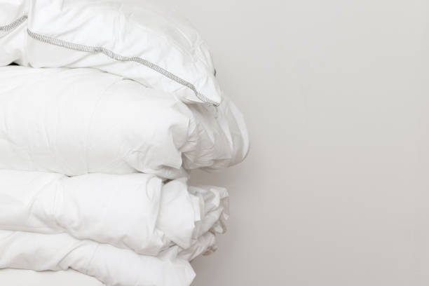 istock Pile of white bedding items, pillows and a blanket on white background with copy space 1184909731