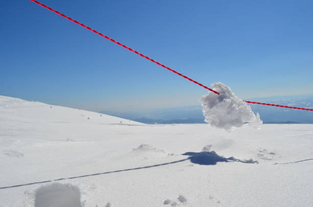 Winter sunny day on high mountain, Lump of frozen snow on red rope after snow blizzard