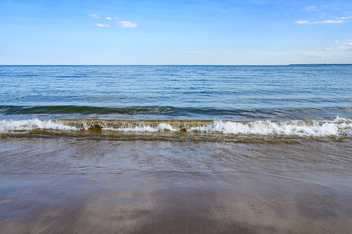 This is a photograph of a Blue Atlantic Ocean Background with Sand On Shore of Coney Island Beach on a Sunny Day