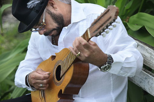 A man playing a folk song in a Puerto Rico Cuatro; a traditional guitar from Puerto Rico.
