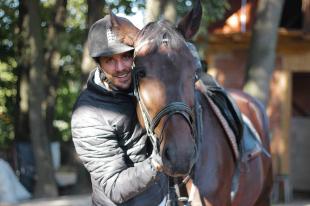 istock Young man stroking a brown horse 1184913743