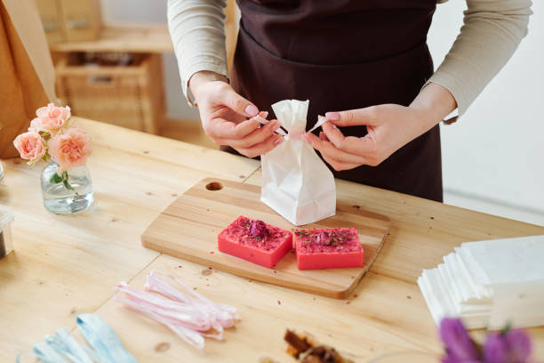 istock Hands of female binding knot on paper packet while packing handmade soap bars 1184920288