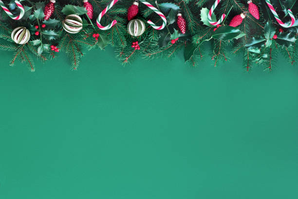 kreatywne świąteczne mieszkanie leżało na zielonym papierze z czerwonymi dekoracjami, dużą ilością miejsca na kopiowanie. naturalna jodła i ostrokrzewy ozdobione laski cukierków, drobiazgi szklane i suchej limonki. - christmas christmas ornament green lime green zdjęcia i obrazy z banku zdjęć