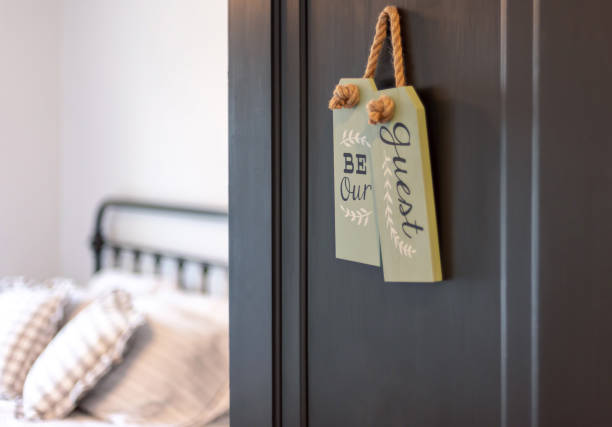 porte ouverte à la chambre d'hôtes avec un signe mignon qui dit "soyez notre invité" - bed and breakfast photos et images de collection