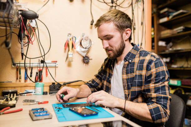 istock Professional repairman with screwdriver repairing broken smartphone in workshop 1184924285