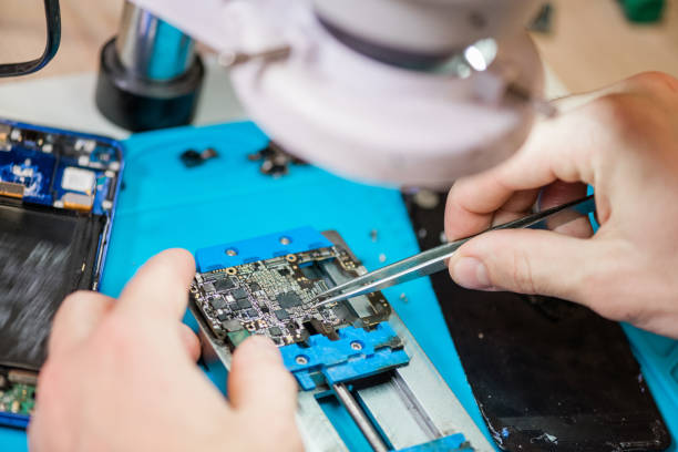 istock Tweezers in hands of repairman using microscope during work with tiny details 1184924287