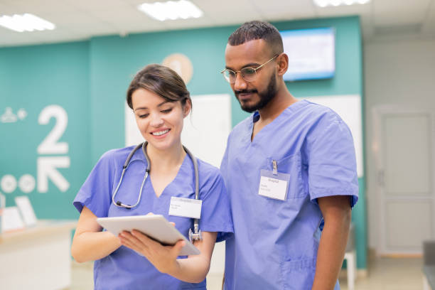 istock Two young successful clinicians in uniform looking through online medical new 1184925788