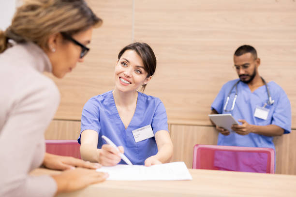 istock Clinician in uniform smiling at patient while pointing at medical document 1184925800