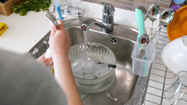 la mujer está lavando cubiertos a mano en la cocina de casa. - silverware clean wet kitchen utensil fotografías e imágenes de stock