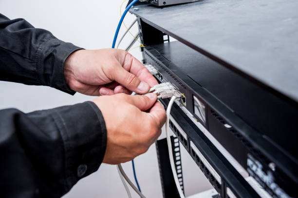 istock Technician connecting network cables to switches. Connecting cables in server cabinet. 1184929188