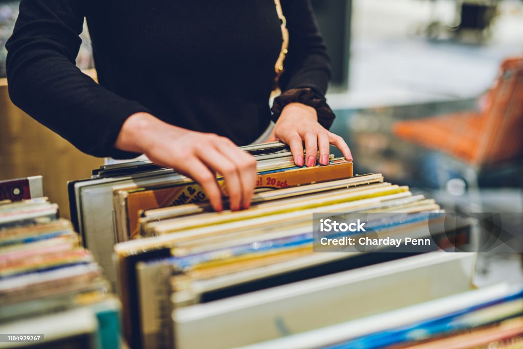 Old school music is the best music Shot of a young woman shopping for vinyl records at a store Record - Analog Audio Stock Photo