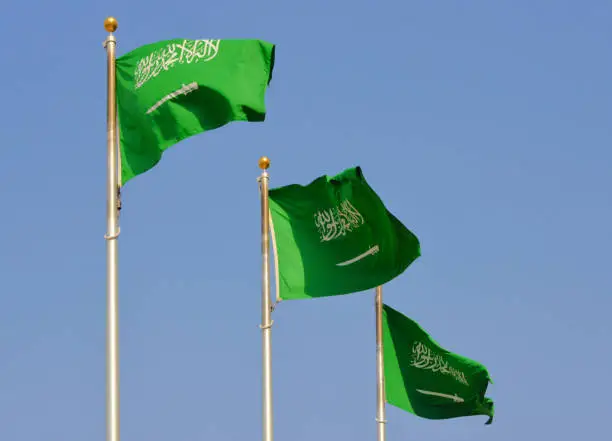 Saudi Arabia, Saudi Arabia: trio of Saudi flags rippled in the wind - sword and the shahada or Islamic profession of faith ("There is no god but God and Muhammad is the Prophet of God") on solid green, originates in the Wahhabi movement.