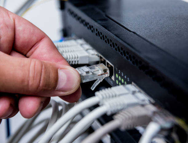 istock Technician connecting network cables to switches. Connecting cables in server cabinet. 1184931491