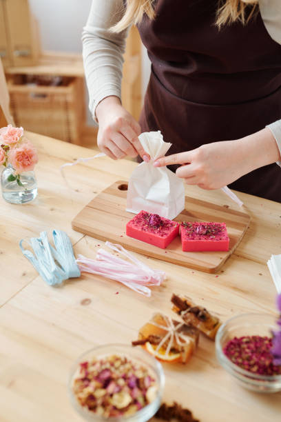 istock Hands of girl binding paper packet with ribbon while packing handmade soap 1184933366