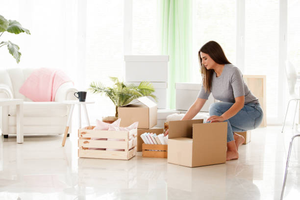 istock Young woman packing boxes for moving house 1184935345