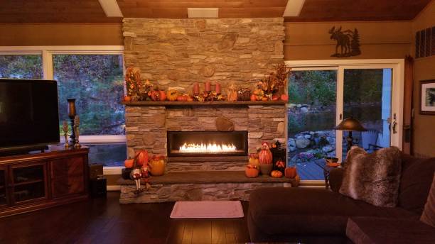 kamienny kominek ścienny ozdobiony jesienno-jesiennymi motywami, oświetlony o zmierzchu - home decorating living room luxury fireplace zdjęcia i obrazy z banku zdjęć