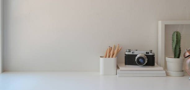 istock Minimal workplace with copy space and office supplies on white wooden table and white wall 1184955926
