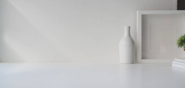 istock Minimal workspace with copy space and mock up frame on white wooden table and white wall 1184955969