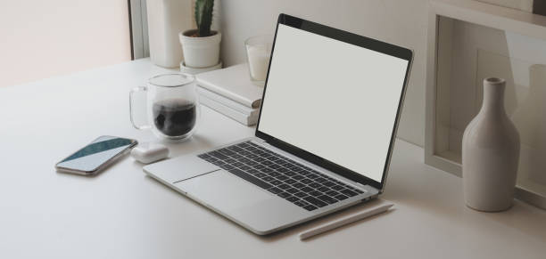istock Minimal workspace with open blank screen laptop computer and office supplies 1184955982