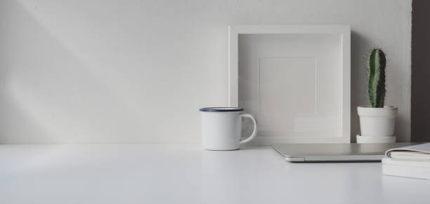 istock Minimal workspace with copy space and mock up frame on white wooden table and white wall 1184956019