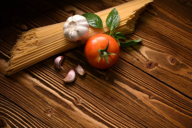 Pasta spaghetti with vegetables and spices on wooden table