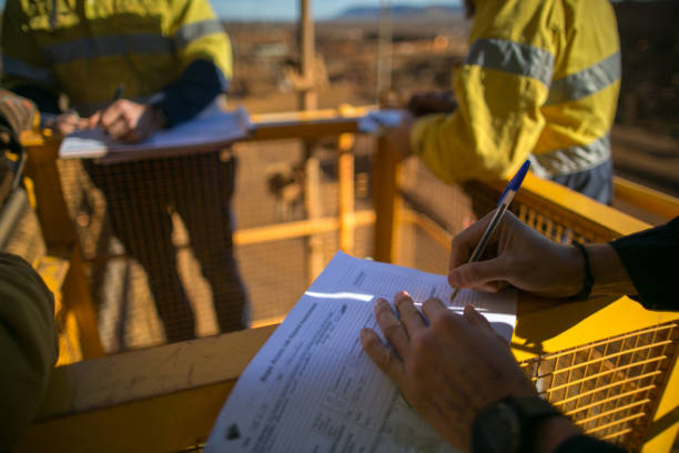 Safety supervisor checking and reviewing document before issued sigh of working at height permit Miner supervisor checking reviewing document before issued sigh of working at height permit JSA risk assessment on site prior to performing high risk work on construction mine site, Perth, Australia miner photos stock pictures, royalty-free photos & images