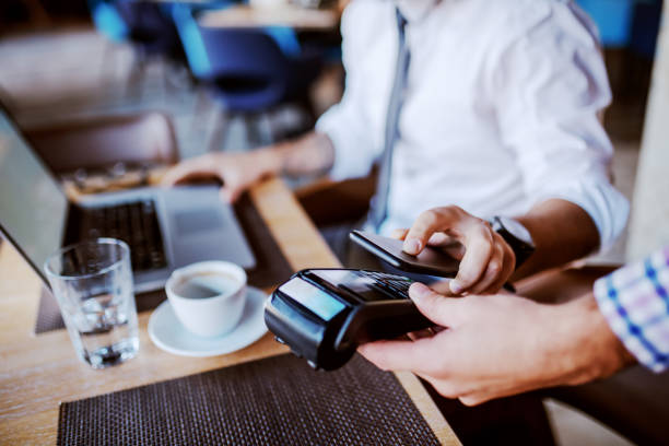 istock Businessman using mobile payment technology to pay bill in coffee shop. 1184972299