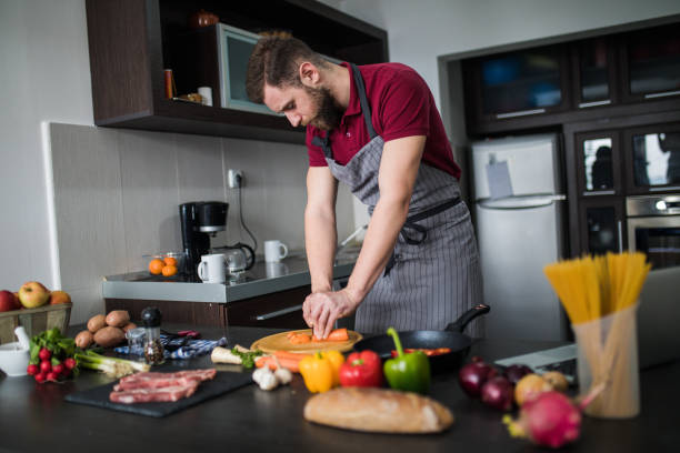 istock Cooker man chopping carrot on kitchen board,close up 1184976514