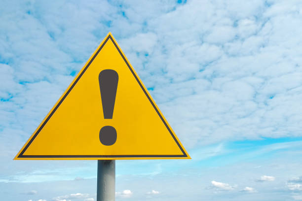 Hazard warning symbol. Attention road sign, yellow background, on sky background. Danger, be careful.