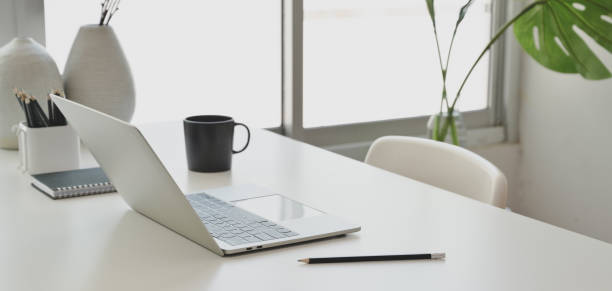 istock Comfortable office room with laptop computer and office supplies on white wooden table 1184979900