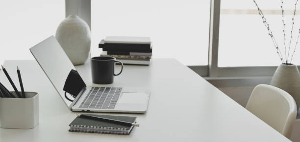 istock Comfortable office room with laptop computer and office supplies on white wooden table 1184980042