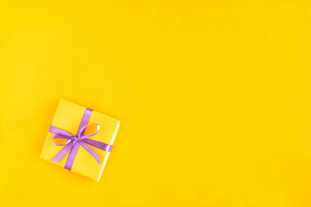 istock Gift box with ribbon and bow on yellow background and space for text. Top view 1184995689