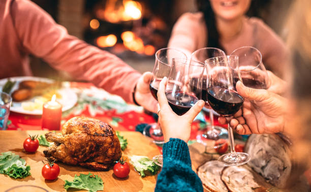 family toasting red wine and having fun at christmas supper party - holiday celebration concept with happy people enjoying winter time together at home dinner fest - warm filter with focus on glasses - chicken roast chicken roasted white imagens e fotografias de stock