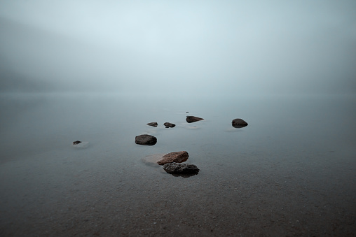 Rocks on the shore, transparent water and dark atmosphere