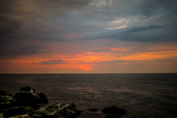 a beautiful sunrise on the ocean. Boat and rocks near the shore