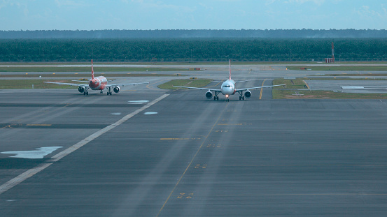 HANOI AIRPORT, VIETNAM, MARCH 2017: Two passenger airplanes meet as they taxi along the runway before take off. Cool view of commercial Air Asia aircrafts driving up and down the empty asphalt road.