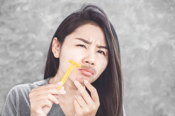 istock Asian woman shaving mustache on face with a razor 1185000623