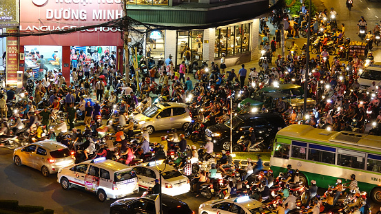 HO CHI MINH CITY, VIETNAM, MARCH 2017 – AERIAL: Countless scooters and cars slowly moving through the crowded streets of Ho Chi Minh during the night time. Commuters creating a large traffic jam.