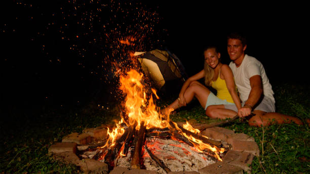 istock CLOSE UP: Cheerful man strikes campfire with stick while snuggling with girl. 1185002076